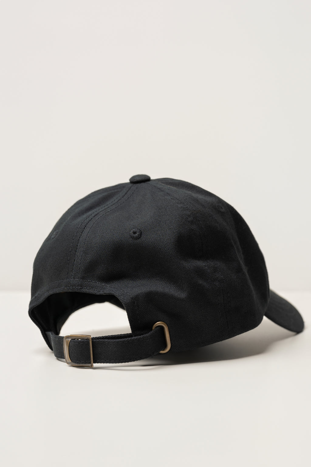 back of a black sojura ballcap with metal strapback adjuster