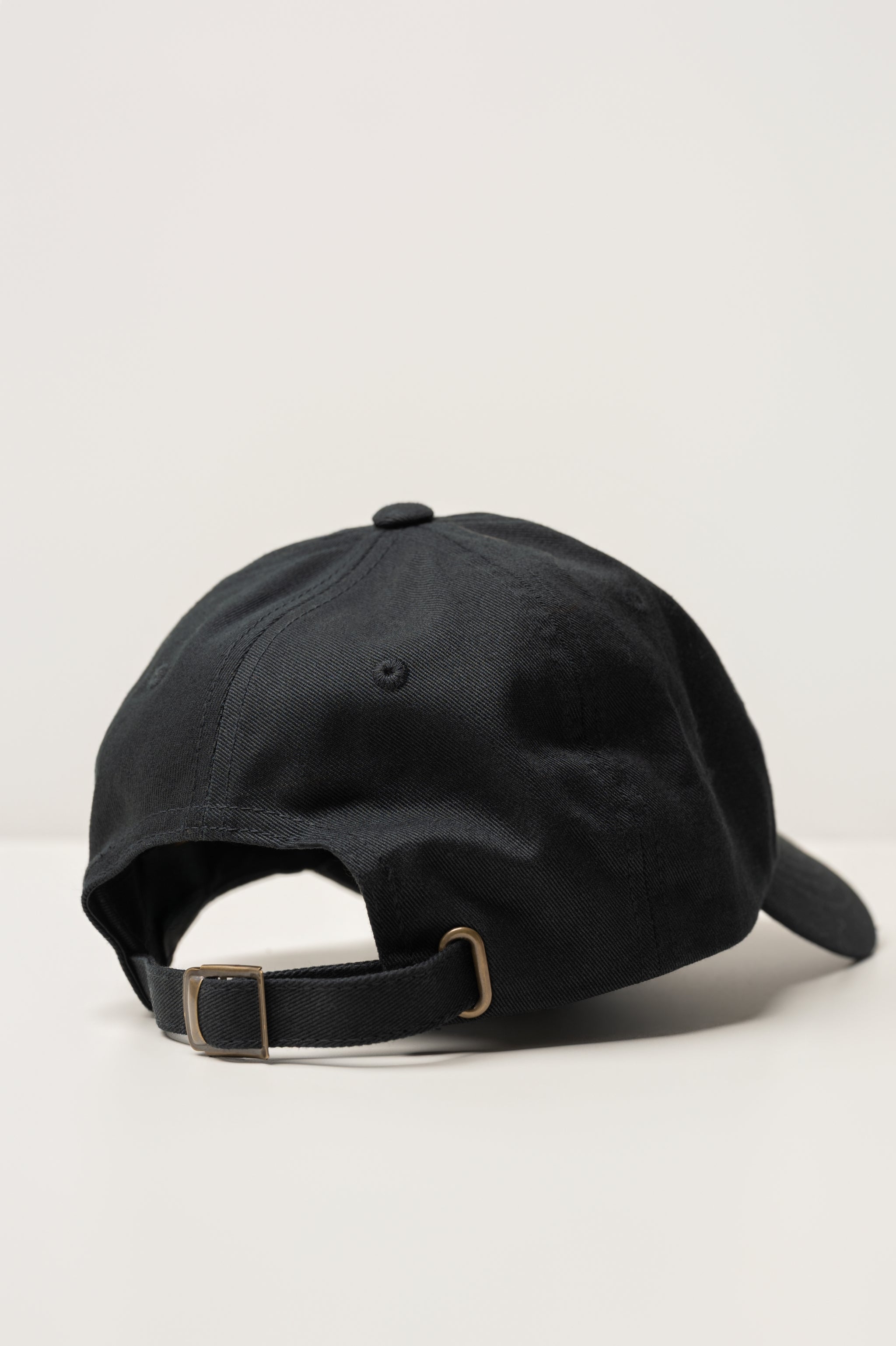 back of a black sojura ballcap with metal strapback adjuster