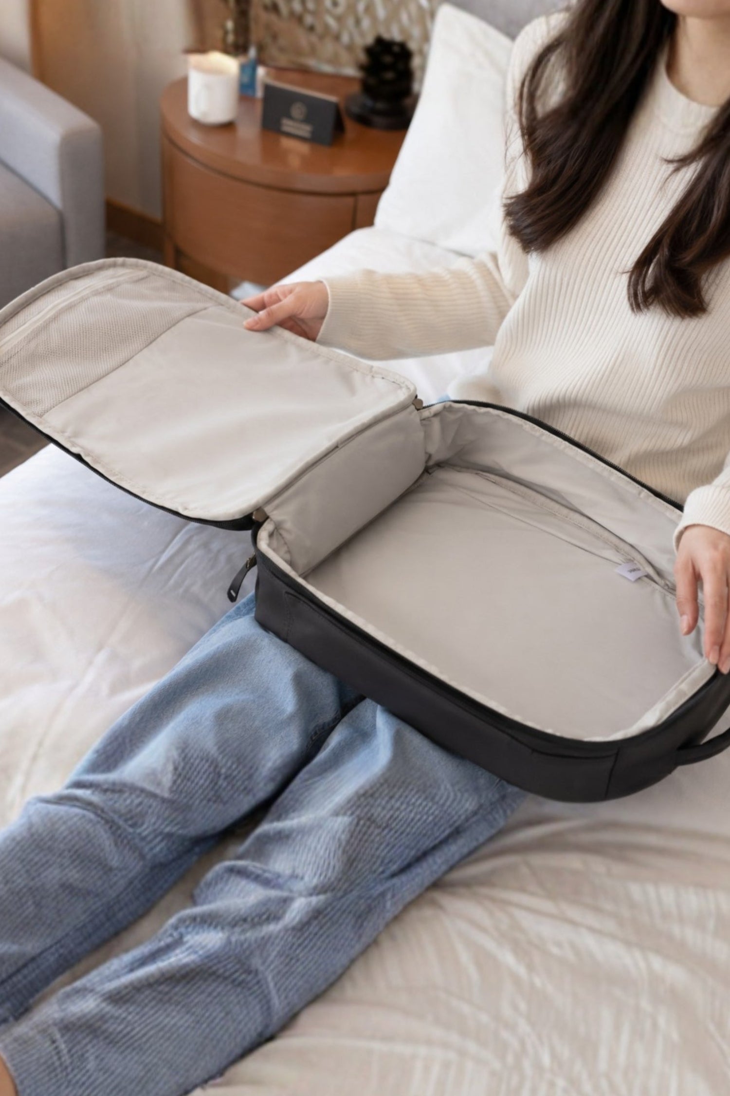 Sojura travel backpack opened all the way like a suitcase on a woman's lap in bedroom