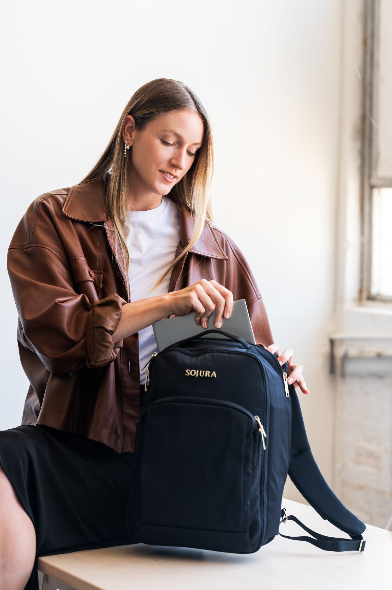 Career woman putting laptop in Sojura womens backpack